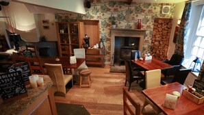 A cozy, well-lit room with a wooden dining table, chairs, a fireplace, and a bookshelf. - Perfect for  all large groups in 7 all ensuite bedrooms . Pet friendly (Buxton)