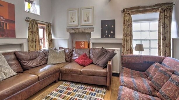 A living room with a brown leather sofa, patterned rug, and a fireplace. - Perfect for  all large groups in 7 all ensuite bedrooms . Pet friendly (Buxton)
