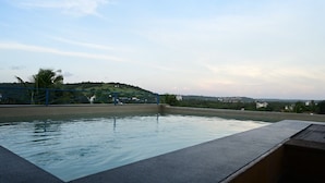 A swimming pool with a view of a hilly landscape and buildings in the distance. - Candolim Suites (Candolim)