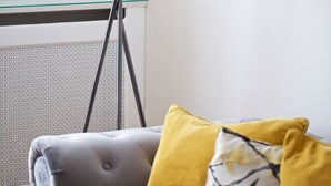 Een moderne woonkamer met een grijze bank, een vloerlamp en een radiator.