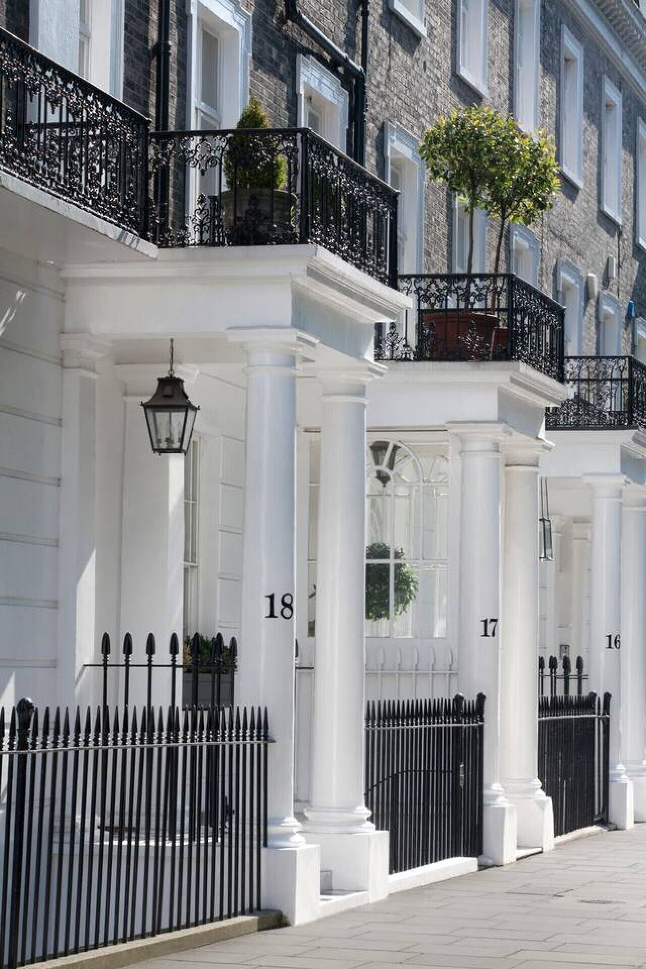 A row of numbered buildings with white facades and black iron railings.