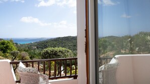 Ein Balkon mit Korbstühlen und Blick auf eine Küstenlandschaft.
