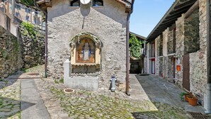 A stone building with a small arched window and a bell. - Rustico Stock With Free Wifi (Monteceneri)