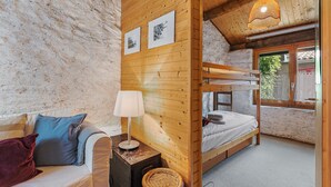 A cozy room with a bunk bed, a sofa with cushions, a lamp, and framed pictures on the wall. - Rustico Stock With Free Wifi (Monteceneri)