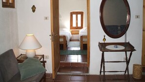 A room with a bed, a bedside table with a lamp, a mirror, and a small table with a sink. - Gemütliches Haus mit Blick zum Meer (Glori)