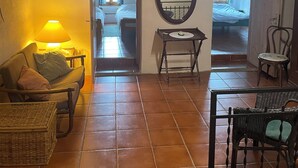 A cozy room with a sofa, a small table, and a chair. There is a mirror on the wall and a door leading to another room. - Gemütliches Haus mit Blick zum Meer (Glori)