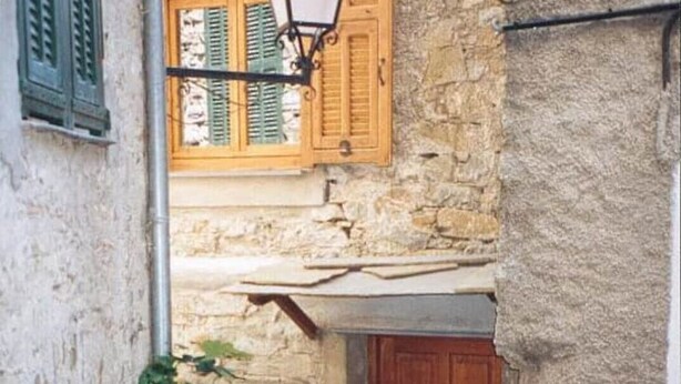 A narrow alleyway with a wooden door and a hanging lantern. There are potted plants and a small step leading to the door. - Gemütliches Haus mit Blick zum Meer (Glori)