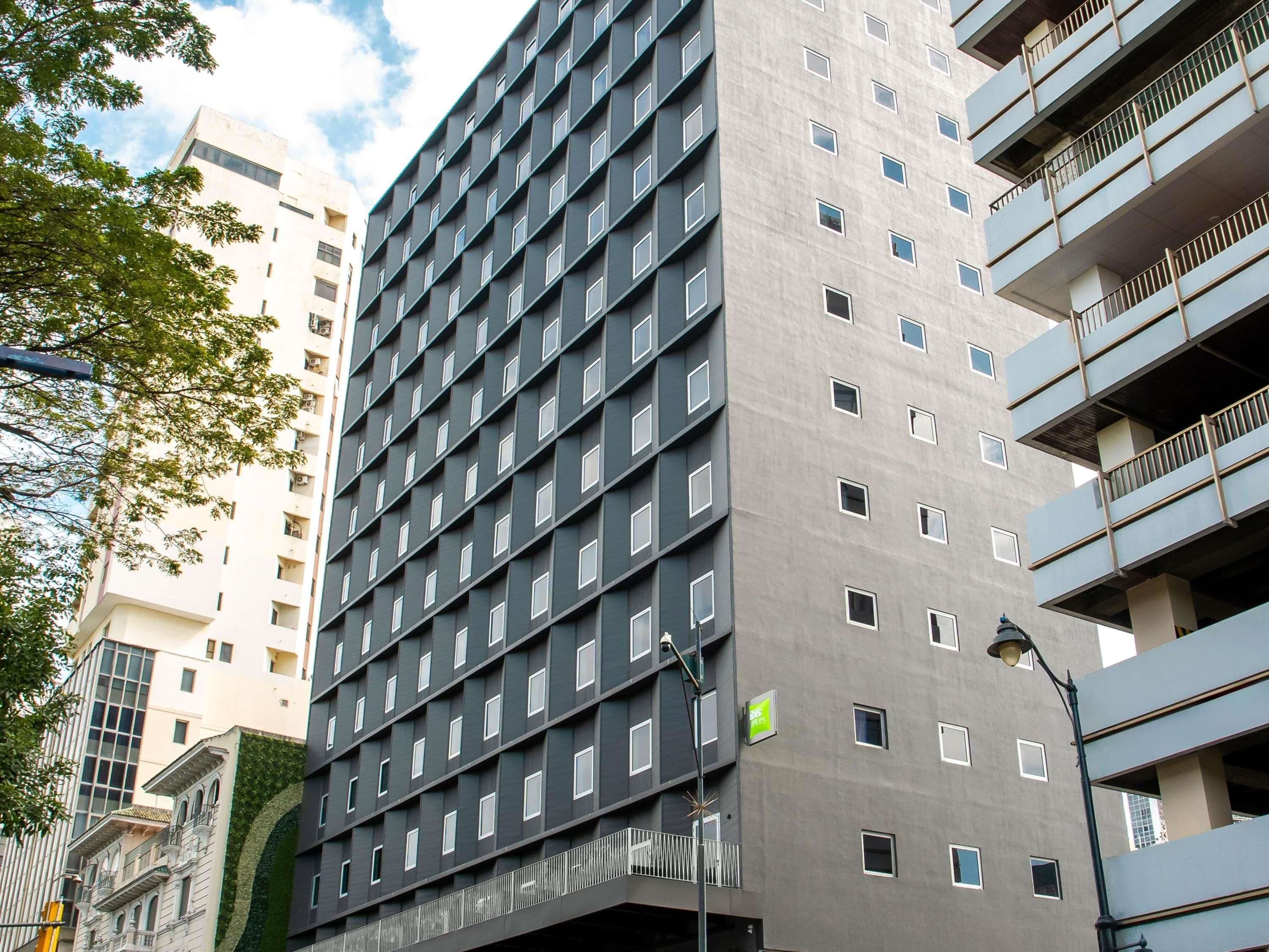 Een meerlaags gebouw met een raster van ramen, een groen bord en een lantaarnpaal.