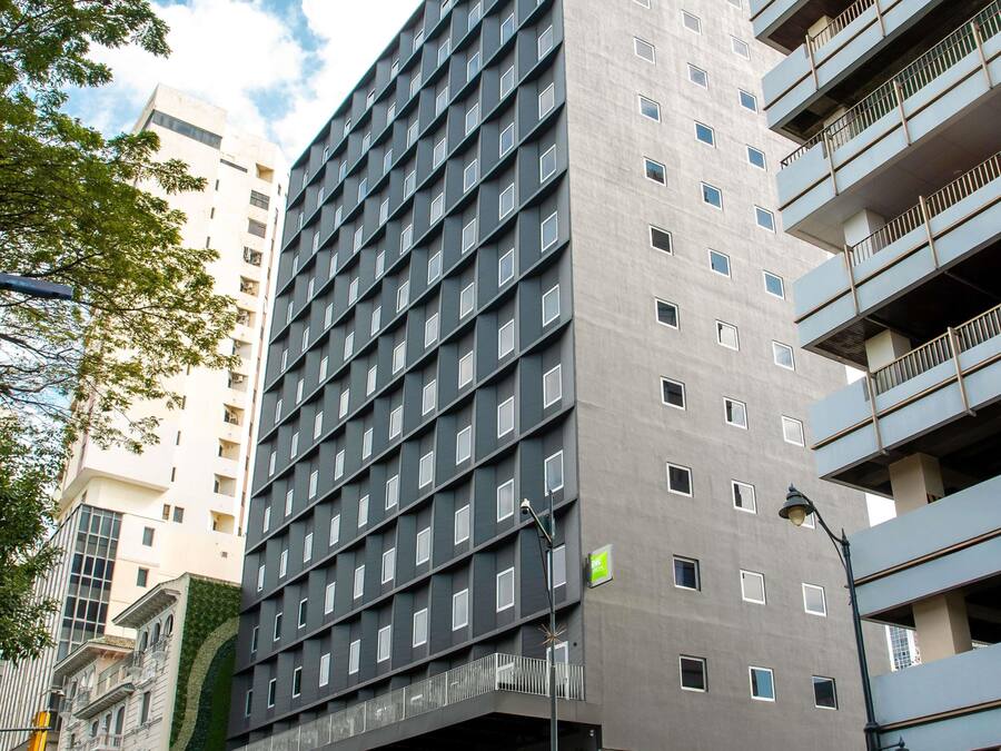 Een meerlaags gebouw met een raster van ramen, een groen bord en een lantaarnpaal.