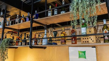 A bar area with multiple shelves of liquor bottles, a coffee machine, and hanging plants.