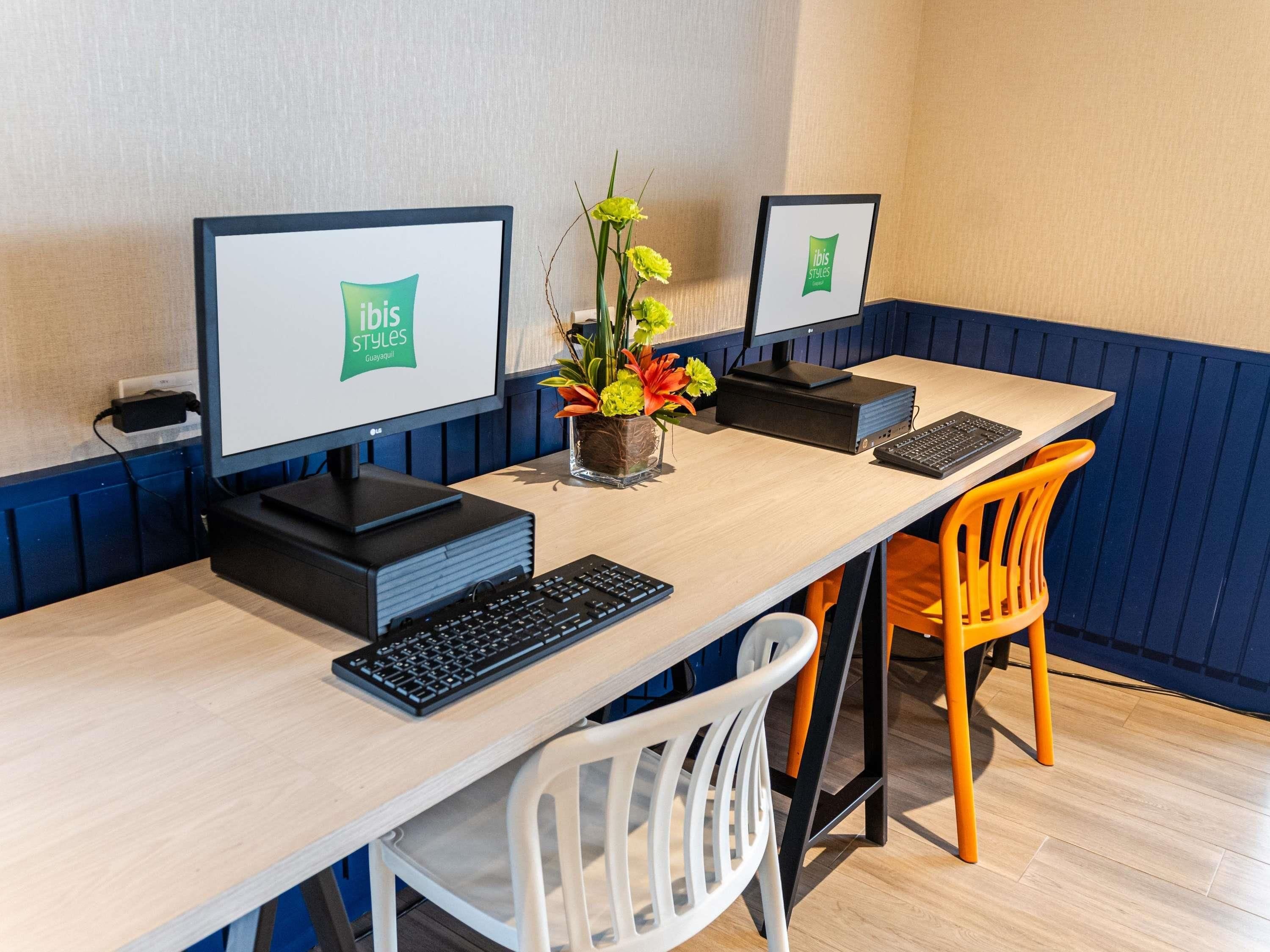 A workspace with two monitors, a keyboard, and a small plant on a wooden table.