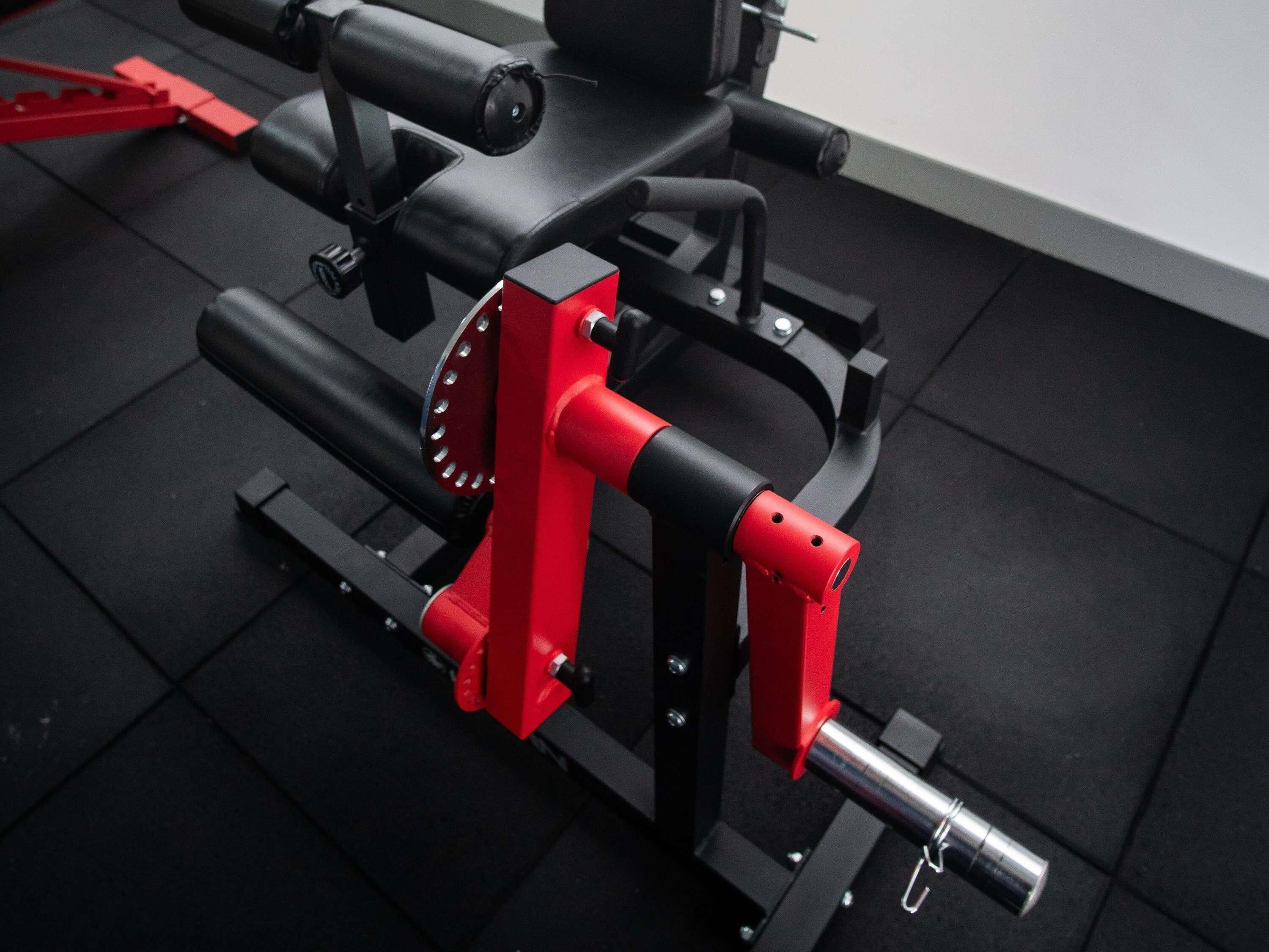 Une salle de sport équipée de matériel d’exercice, notamment une machine rouge et noire et un banc de musculation noir.