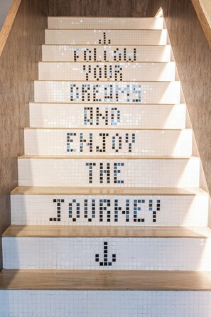 Una escalera con mosaicos que deletrean "SIGUE TUS SUEÑOS Y DISFRUTA EL VIAJE".