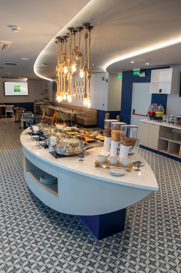Een buffetopstelling met diverse gerechten, een moderne kroonluchter en een vloer met een patroon.