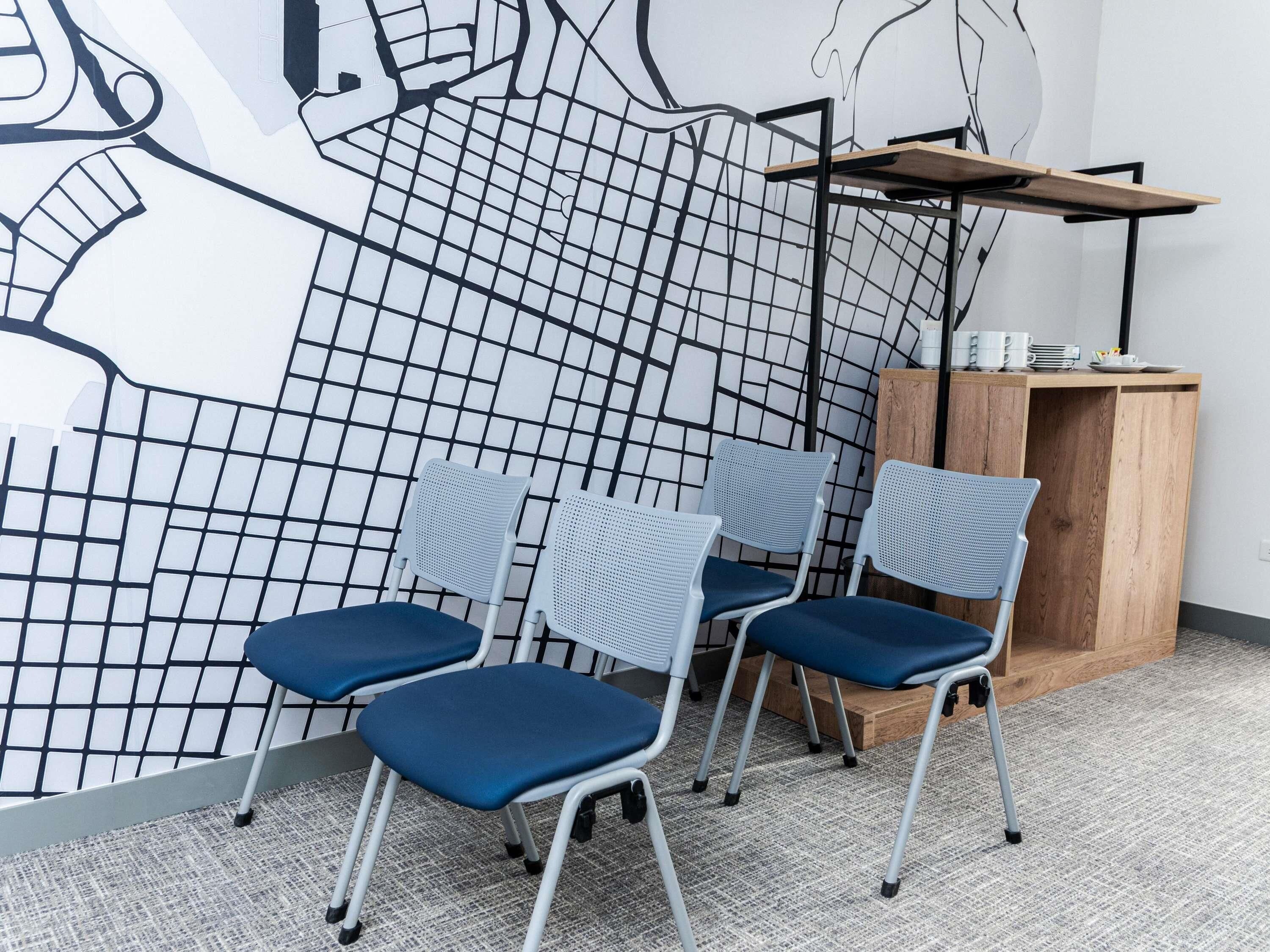 Una habitación con cuatro sillas, un aparador de madera y una pared con un diseño geométrico.