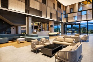 A spacious lobby with a modern design, featuring a seating area with sofas and chairs, a coffee table, and a reception desk. - Ibis Yogyakarta Airport Kulon (Temon)