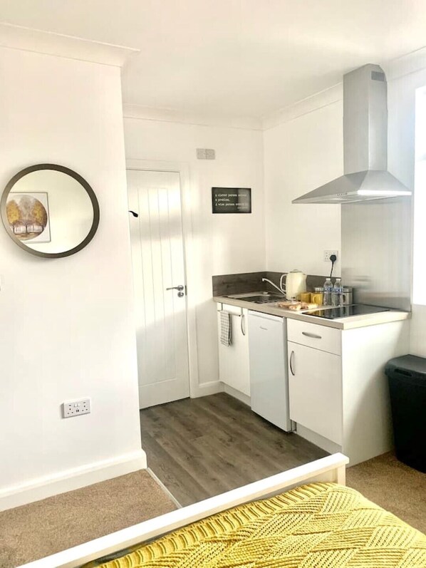 Kitchen with stainless steel range hood, sink, and various kitchen utensils.