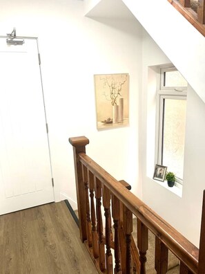 Staircase leads to an upper floor, with a framed picture and a potted plant adding a touch of warmth.