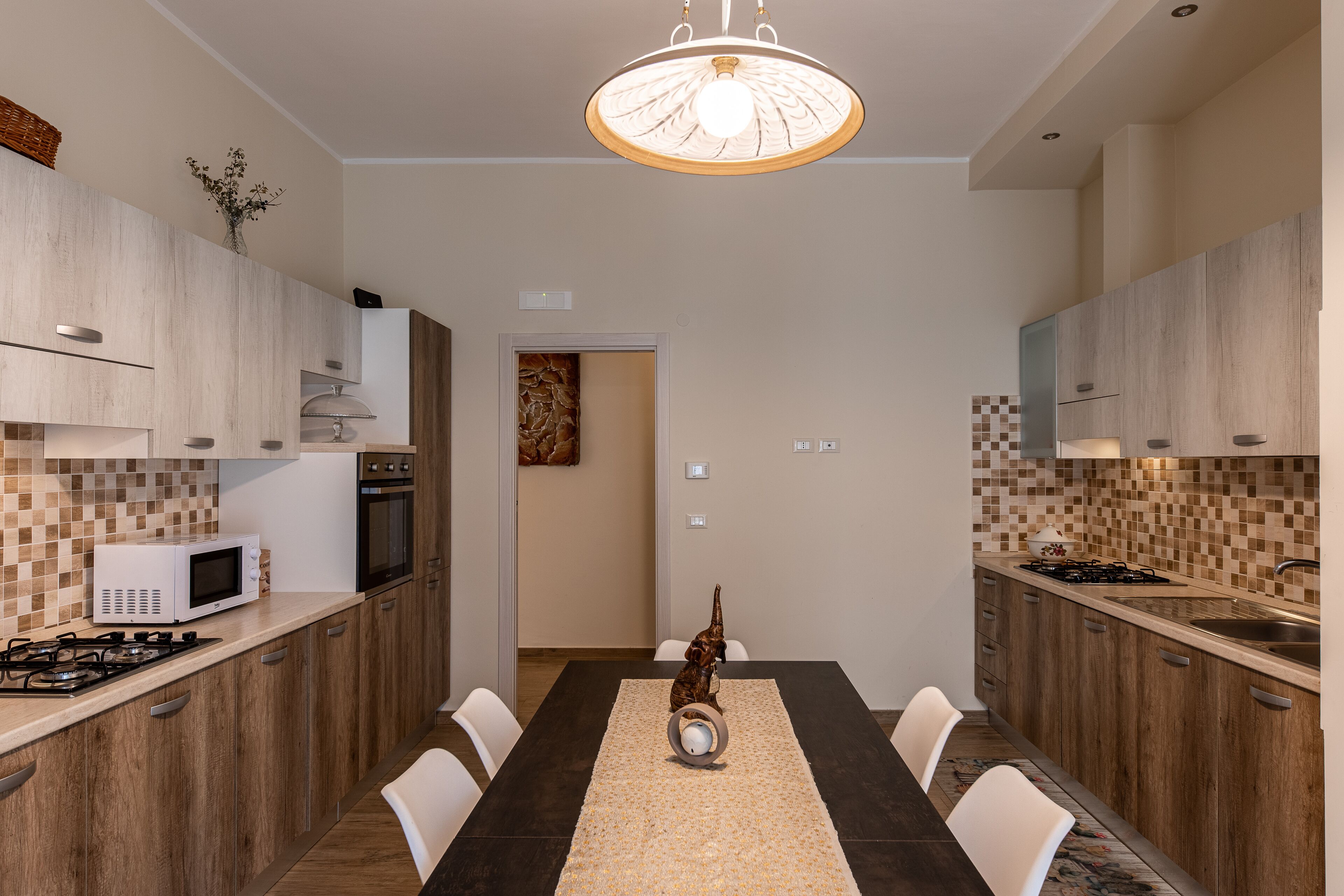 Una cocina moderna con armarios de madera, una mesa de comedor y una lámpara de araña.