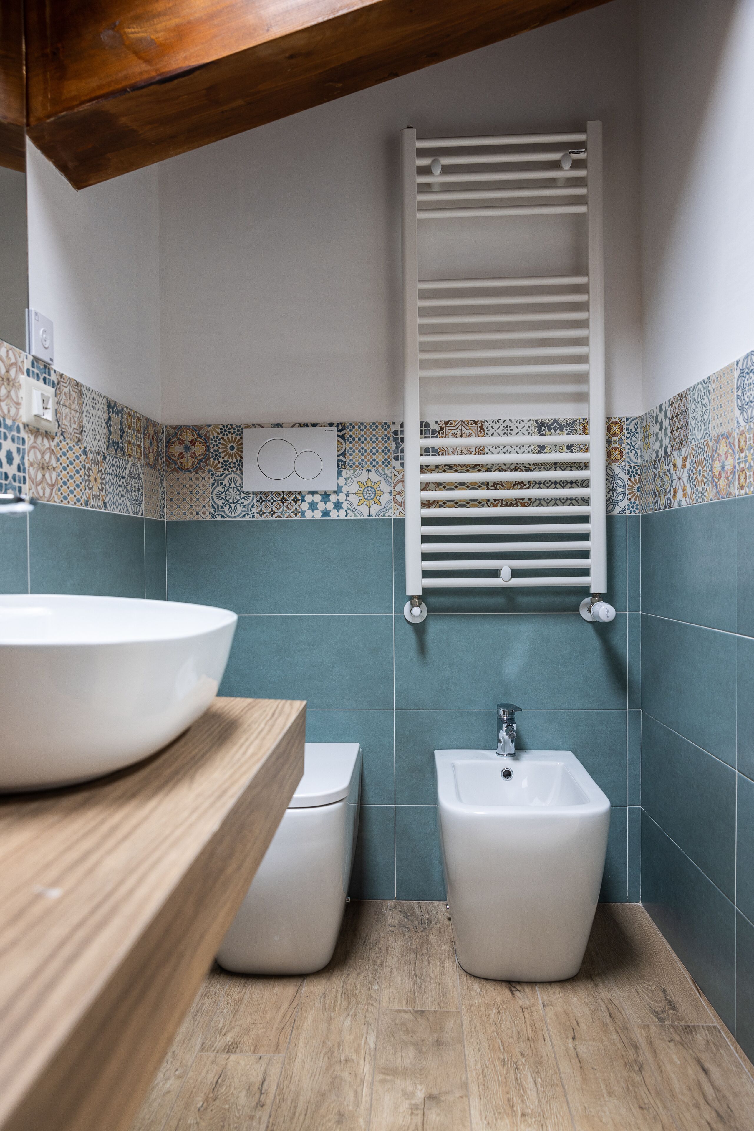 Un baño con un lavamanos blanco, un bidé y un perchero para toallas.