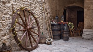 A rustic stone wall with a wooden cart wheel, barrels, wicker baskets, and wicker chairs. - AGORA' CASTELNUOVO DELLA DAUNIA (Castelnuovo della Daunia)