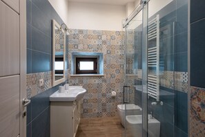A bathroom with a tiled backsplash, a window, a sink, a toilet, and a shower area. - AGORA' CASTELNUOVO DELLA DAUNIA (Castelnuovo della Daunia)