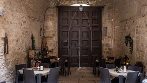 An interior with stone walls, a large wooden door, and tables set for dining. - AGORA' CASTELNUOVO DELLA DAUNIA (Castelnuovo della Daunia)