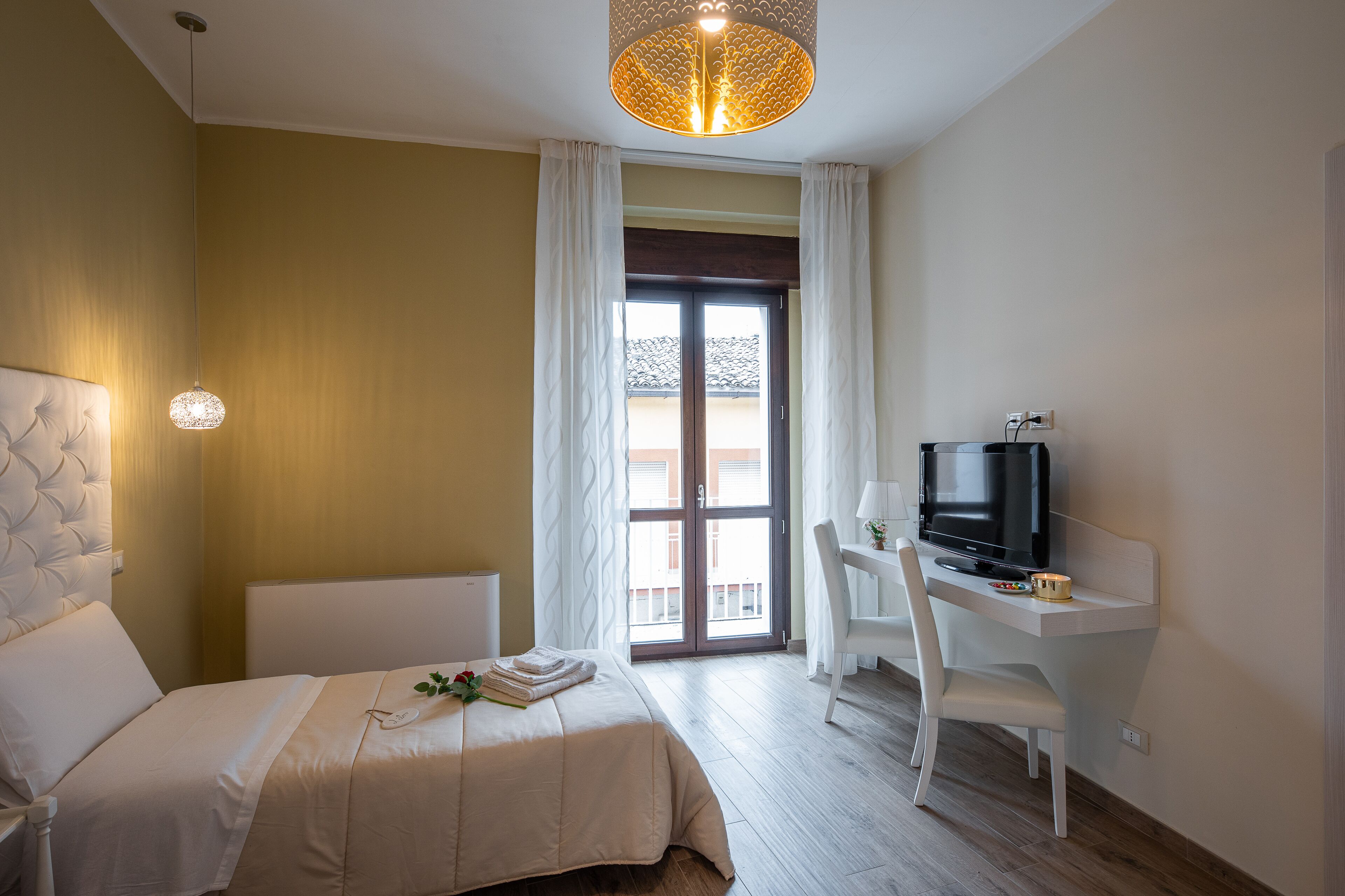 Habitación de hotel con cama, escritorio con televisor y vista a través de un ventanal.