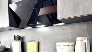 A modern kitchen with a stainless steel countertop, a built-in oven, and a coffee maker.