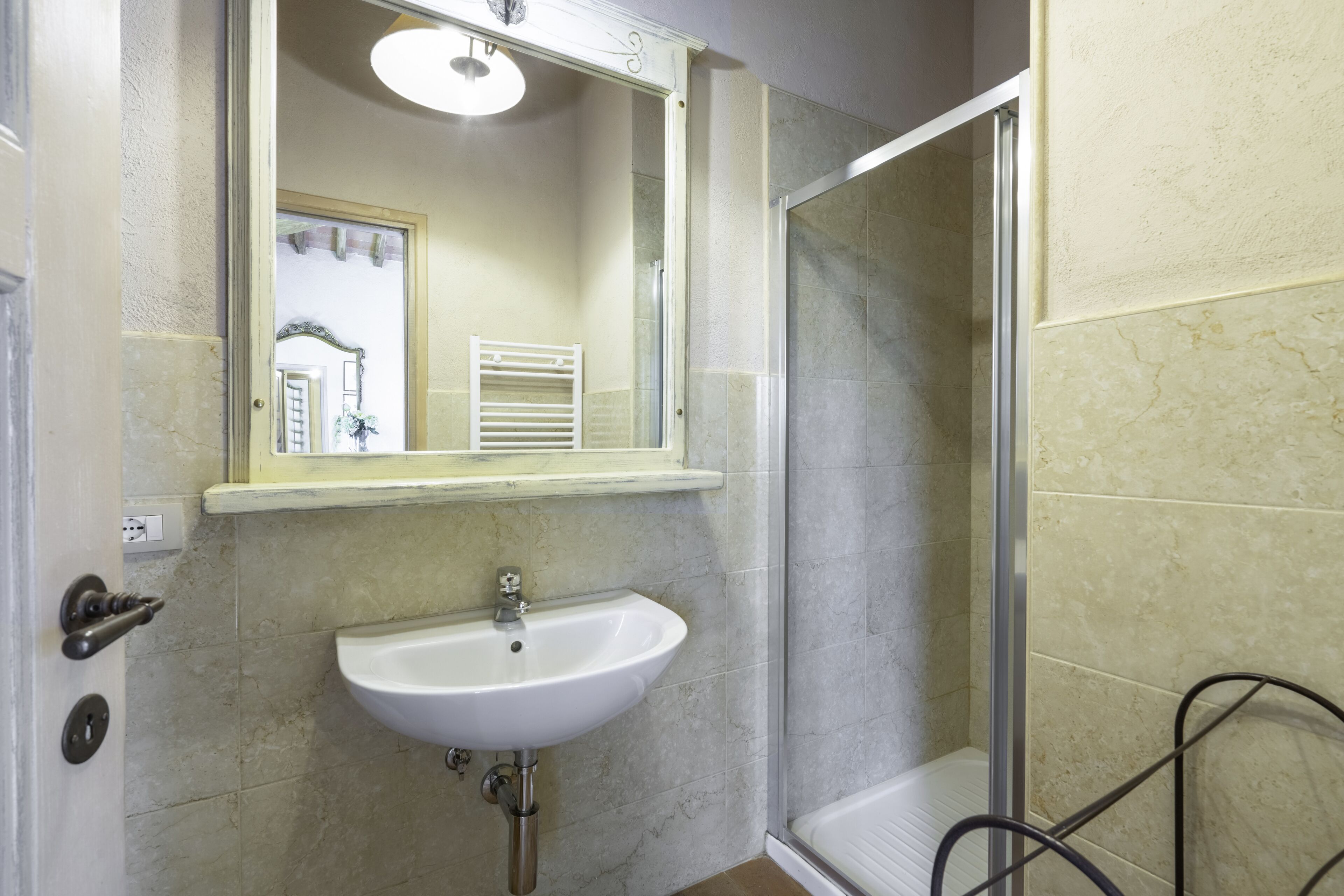 A bathroom with a white sink, a mirror, and a shower area.
