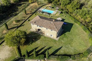 A stone building with a tiled roof, surrounded by a well-maintained lawn and a swimming pool. - Leopolda In Selvarella By Geco Vacation Rentals (Bucine)