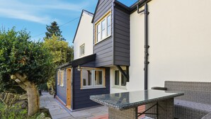 A modern house with a balcony, outdoor furniture, and a tree. - Laburnum Cottage (Tarporley)