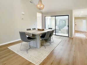 A modern dining area with a large table, grey chairs, and a woven rug. - 2 Turtle Lane at The Sea Pines Resort (Hilton Head Island)