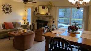 A cozy living room with a fireplace, a dining area, and a view of a lake. - Fishing, skiing, golfing, water parks, restaurants, outlets  , family activity (Blakeslee)