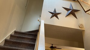 A staircase with carpeted steps leading to a landing with a ceiling fan and decorative stars. - Fishing, skiing, golfing, water parks, restaurants, outlets  , family activity (Blakeslee)