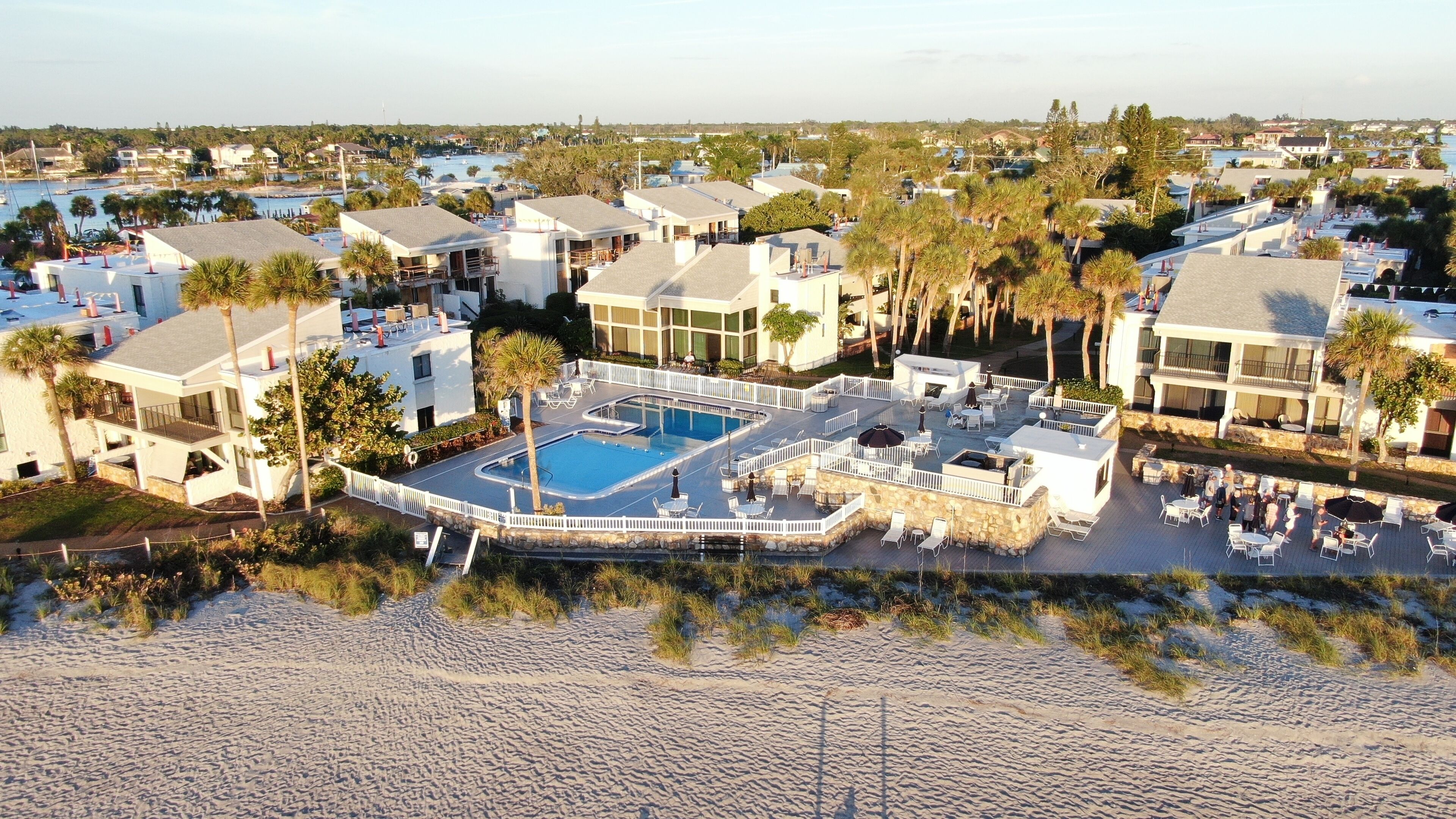Et resort med pool i centrum, flere bygninger og en strand.