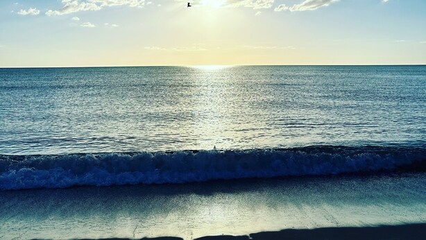 Een strand met heldere lucht, zon en oceaan golven.