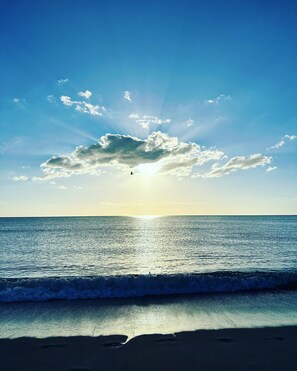 Ein Strand mit blauem Himmel, Sonne und Meereswellen.