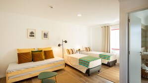 Una habitación con dos camas, una mesita y una silla. Dos cuadros enmarcados decoran la pared.