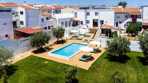 Un barrio residencial con piscina, mobiliario exterior y césped cuidado.