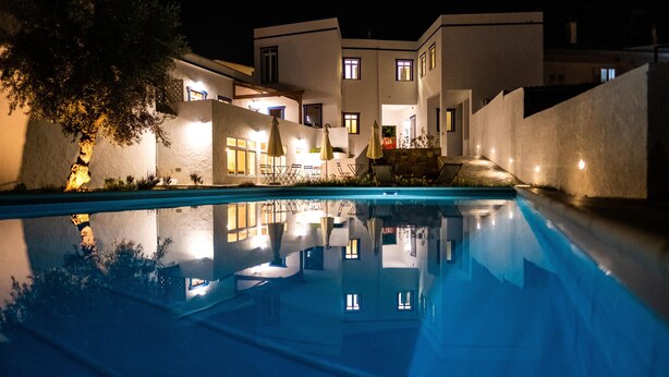 Un edificio moderno con piscina, varias ventanas y zonas de estar al aire libre.