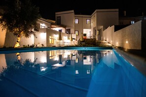 A modern building with a swimming pool, multiple windows, and outdoor seating areas. - A Casa da Cerca (Almodôvar)