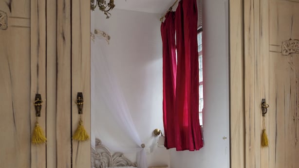 A room with a large mirror reflecting a bed with white bedding and a red curtain. - Viareggio Sea & Garden (Viareggio)