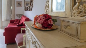 A room with a vintage dresser, a red sofa, and a vase of flowers on the dresser. - Viareggio Sea & Garden (Viareggio)