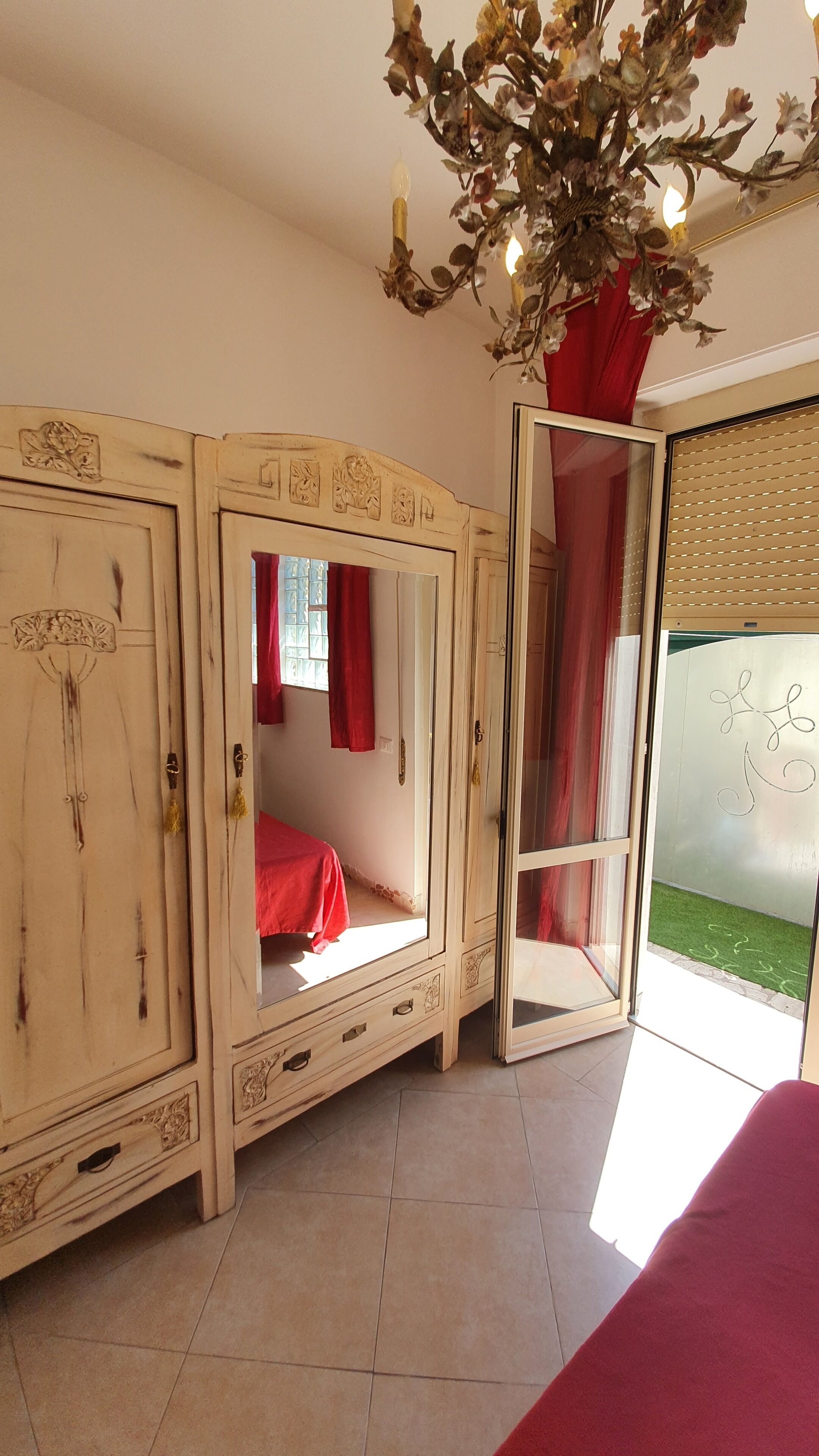 Een kamer met een grote garderobe, een spiegel en een rood beddegoed.