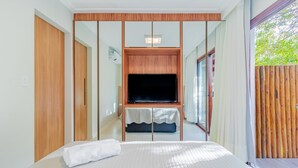 Een moderne hotelkamer met een groot bed, een flatscreen televisie bevestigd aan een houten paneel en een glazen schuifdeur naar een balkon.
