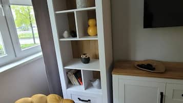 A room with a white cabinet, a yellow chair, and a television on the wall.