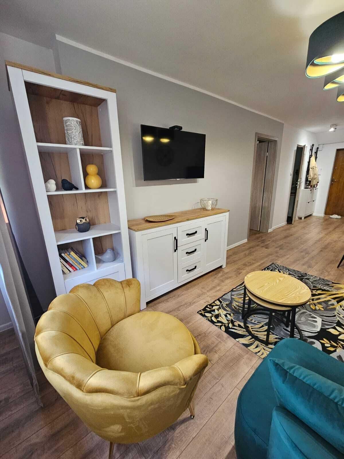 Una sala de estar moderna con un sofá, una mesa de centro, un televisor montado en la pared y una estantería.