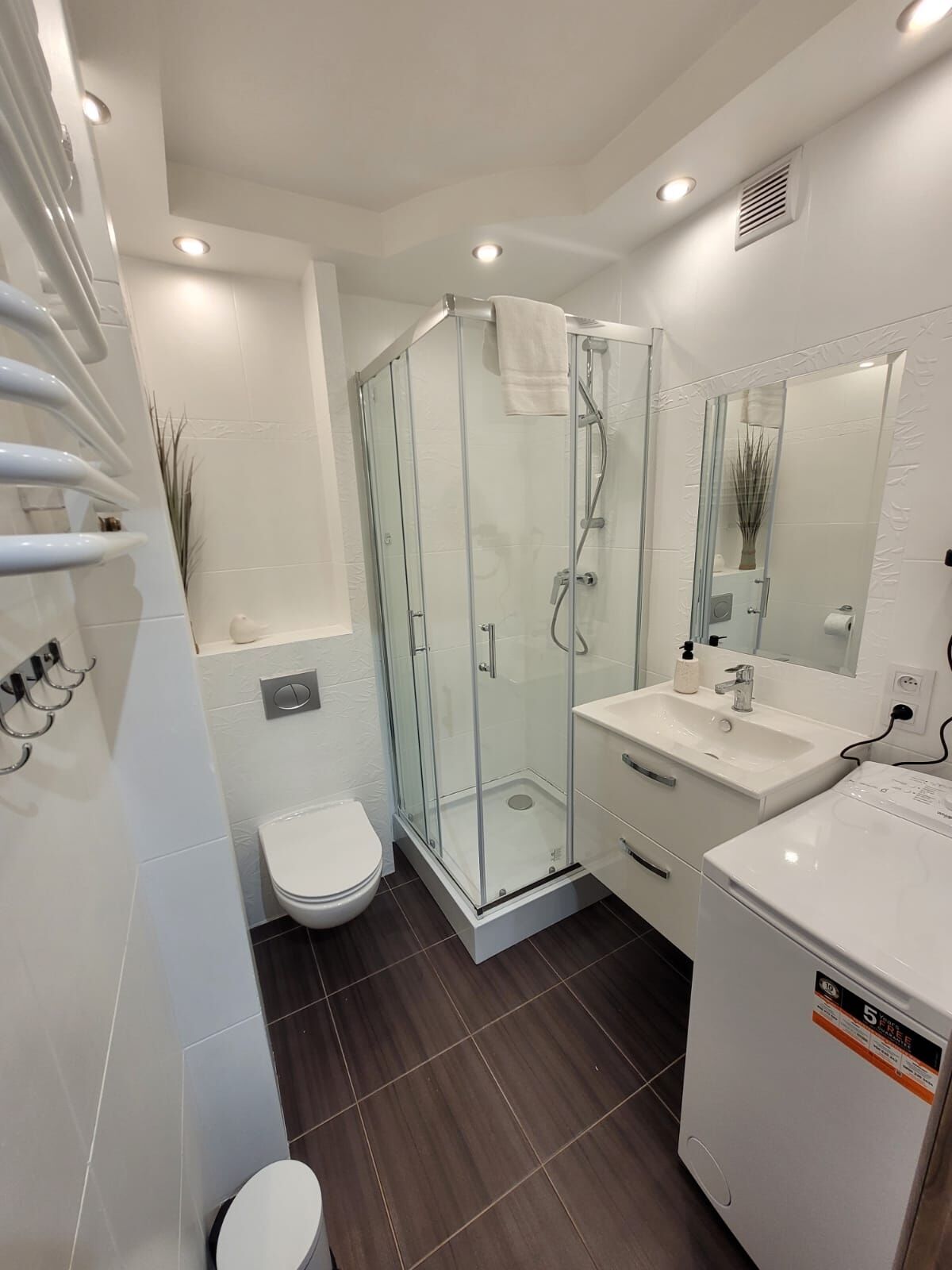 Une salle de bain moderne avec une douche à parois de verre, un lavabo blanc et des toilettes.