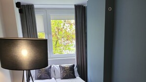 Un dormitorio con cama, lámpara de pie, una pequeña mesa redonda y una silla.